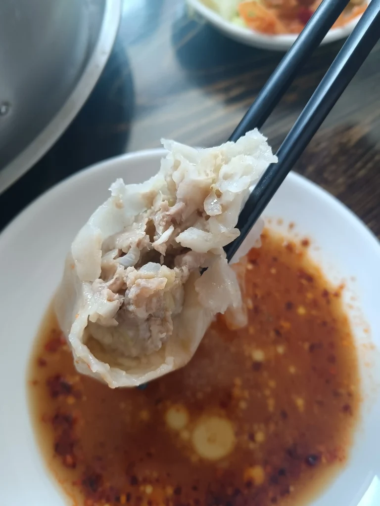 Chopsticks picking up a juicy Hohhot shaomai dumpling